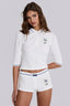 Model wearing a white cropped polo shirt with blue trim and matching white shorts with blue trim.