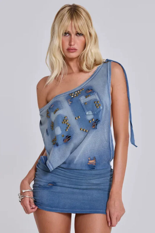 Woman wearing a distressed denim one-shoulder dress with cut-outs and stud embellishments.