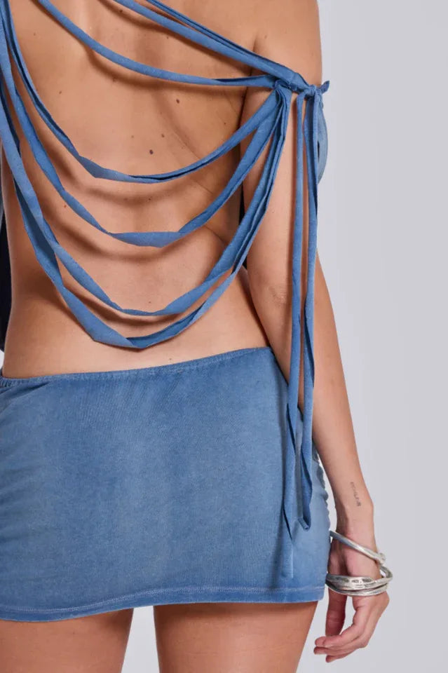 Close-up of the back of a distressed denim dress with strappy detailing.