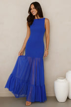 woman wearing a royal blue sleeveless maxi dress with a sheer tiered ruffle hem
