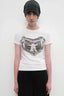 Model wearing a white crew neck t-shirt with a black and white graphic print on the chest and a black and grey striped beanie.