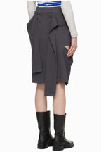 Side view of a grey graphic print midi skirt with cut-out details and a tie detail, showing the asymmetrical hem and layered fabric.