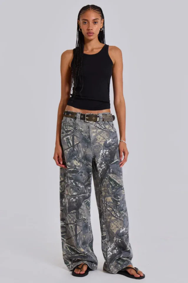 Woman wearing a black tank top and camouflage wide-leg jeans, standing from the front.