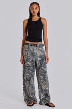 Woman wearing a black tank top and camouflage wide-leg jeans, standing from the front.