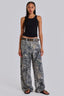 Woman wearing a black tank top and camouflage wide-leg jeans, standing from the front.