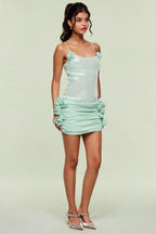 Side view of a woman wearing a light blue sequined mini dress with floral appliques and ruched detailing.