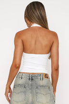 Back view of a woman wearing a white ribbed halter top, showing the open back design.