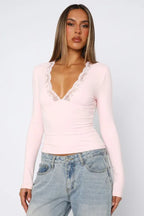 Woman wearing a pink long-sleeved top with lace trim and blue jeans, front view