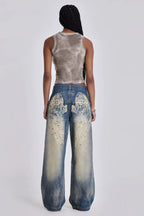 Model wearing wide leg jeans with a grey tank top, back view showing graphic detail.
