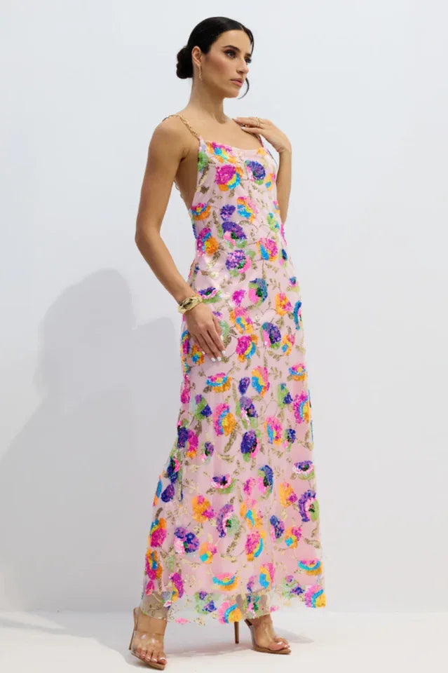 Woman wearing a pink floor-length gown with colorful floral sequins and gold chain straps, standing against a white background. Main image