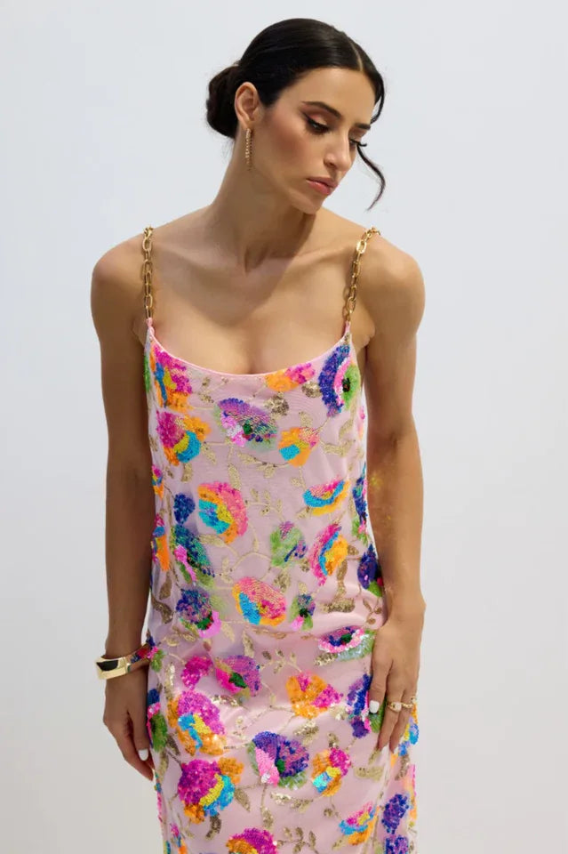 Close-up of a woman's torso in a pink sequined floral gown with gold chain straps.