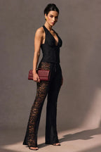 Side view of a woman in a black lace halter top and flared pants