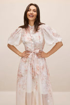 Close-up of a woman smiling in a floral midi dress.
