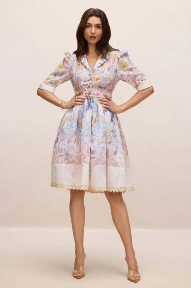 Full body shot of a woman posing in a floral print midi dress with her hands on her hips