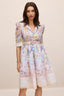 Woman wearing a floral print midi dress with puff sleeves and a belted waist