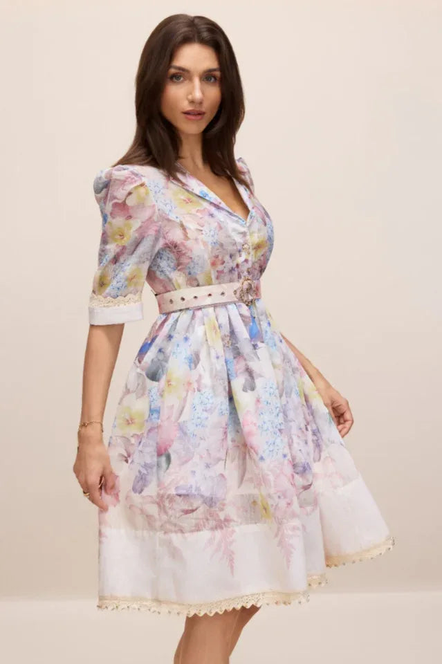 Side profile of a woman in a floral print A-line dress with puff sleeves and lace trim