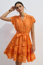 Woman wearing an orange lace-trimmed dress with a tie waist.