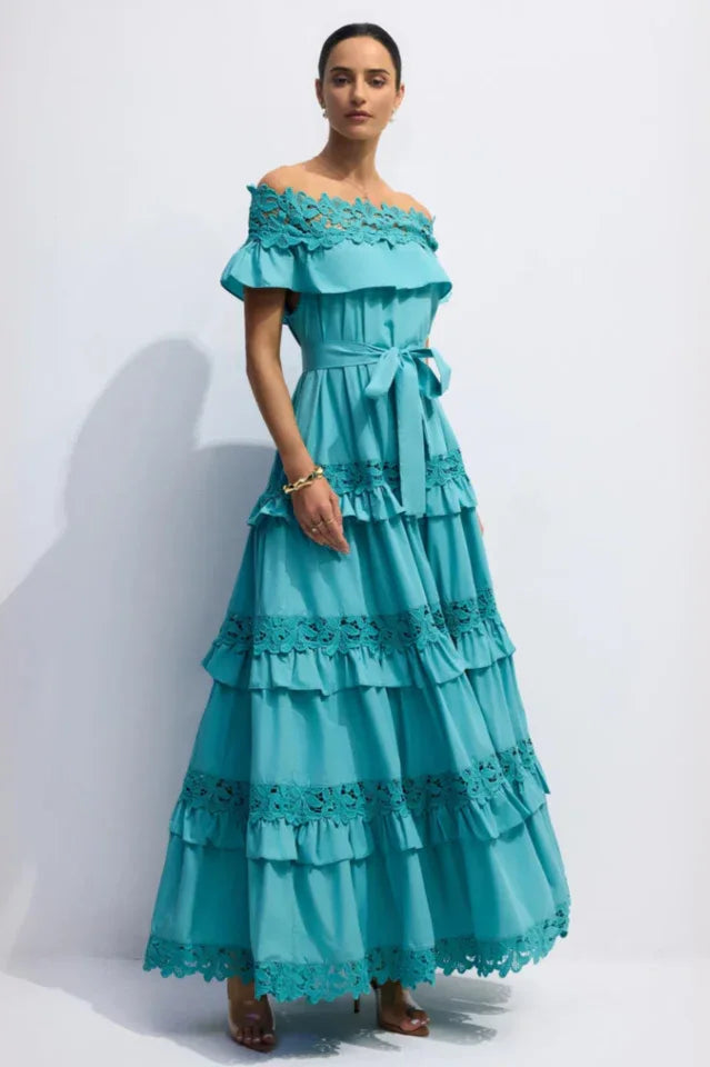 Full-length view of a woman in a turquoise tiered maxi dress with lace accents and a self-tie belt.