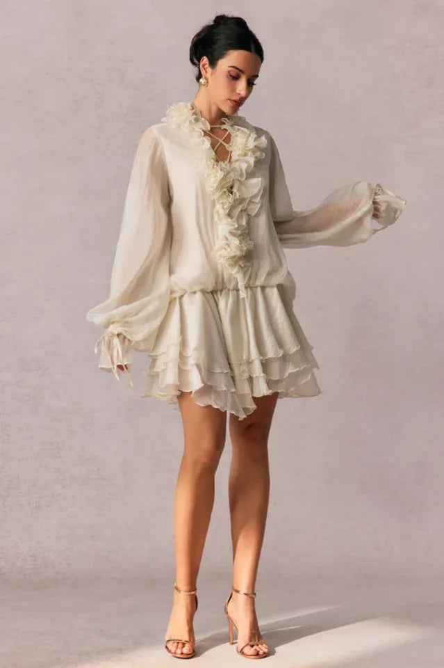 woman posing in a white chiffon dress with layered skirt and dramatic sleeves