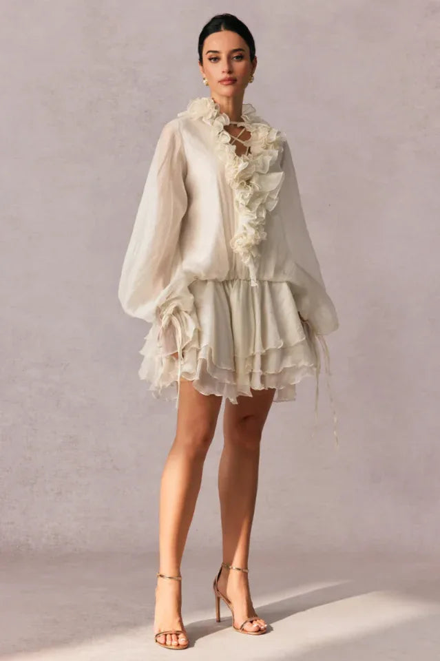 full body shot of a woman in a white ruffled mini dress with bishop sleeves Secondary image