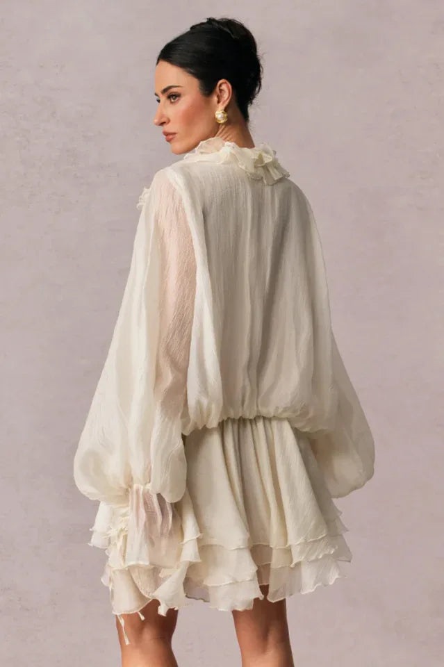 back view of a woman in a white ruffled mini dress