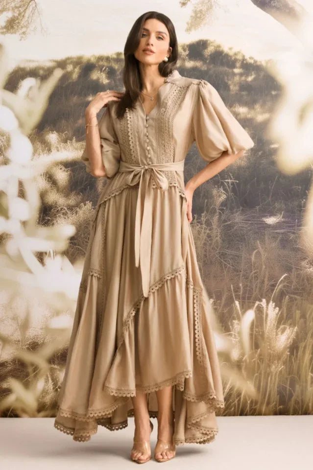 Woman wearing a tan linen blend maxi dress with puffed sleeves and a tiered skirt.