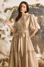 Close-up of a woman's upper body wearing a tan linen blend maxi dress with lace detailing on the bodice and puffed sleeves.