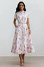 Woman wearing a white midi dress with a floral print, short sleeves, and a belted waist, standing against a white background.