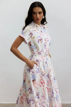 Close-up of a woman's torso in a floral print midi dress, highlighting the button details and belted waist.
