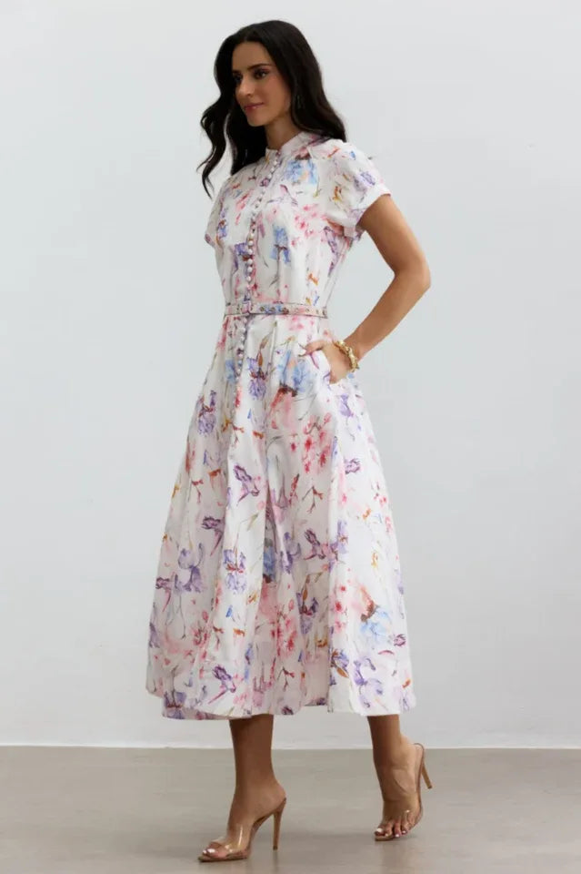 Side view of a woman in a floral print midi dress with a collared neckline and short sleeves.