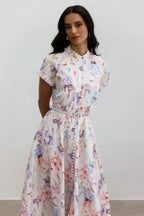 Woman from the back wearing a floral print midi dress with a collared neckline and short sleeves.
