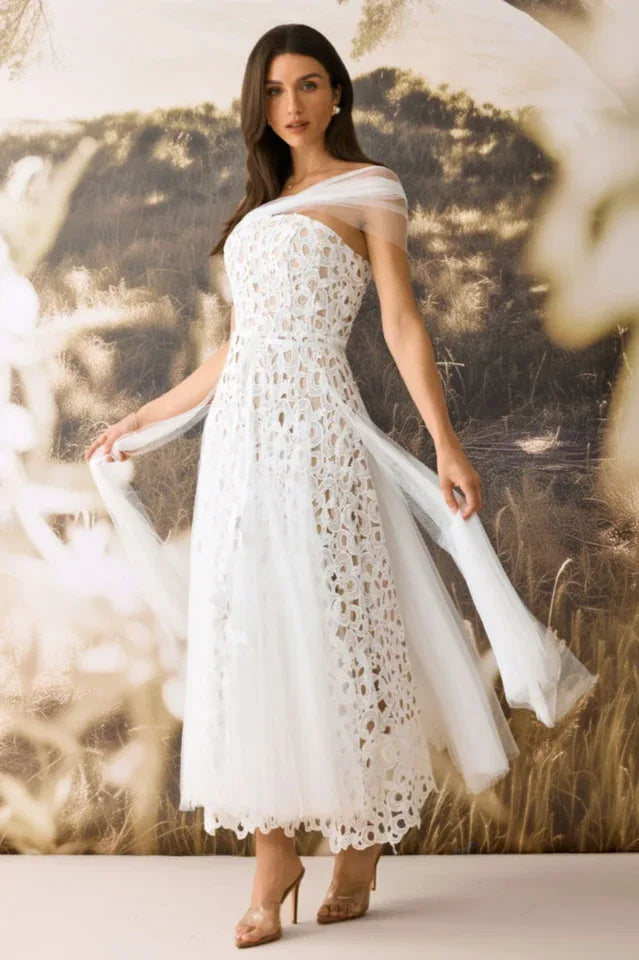 Full-length view of a woman in a white lace dress with flowing tulle sleeves. Secondary image