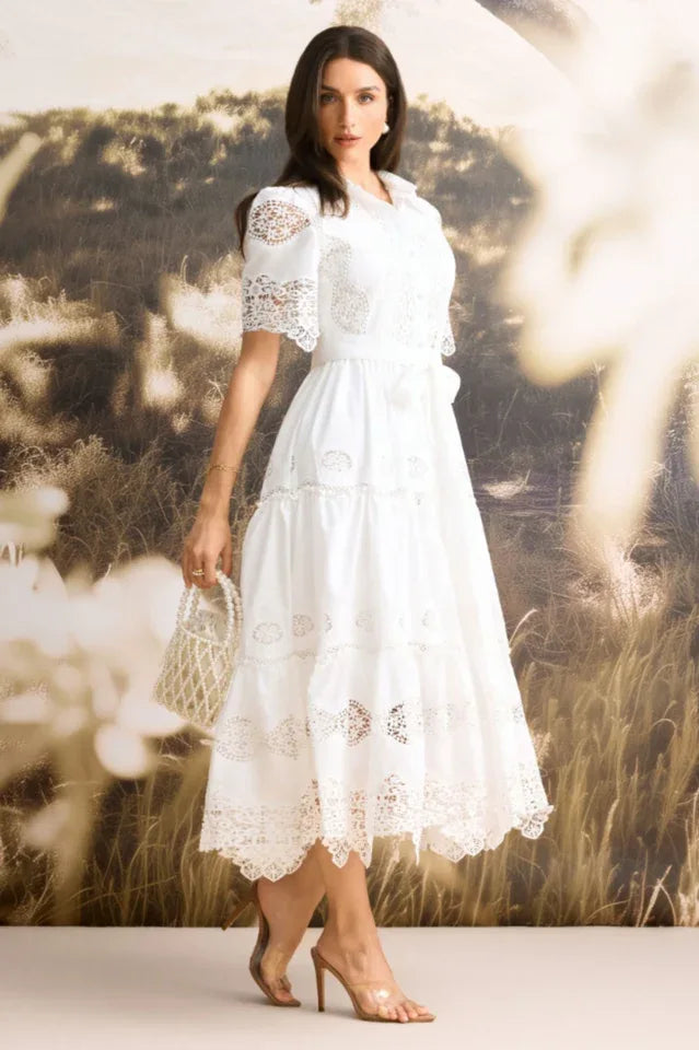 Side view of a woman in a white lace midi dress with short sleeves and a collared neckline.