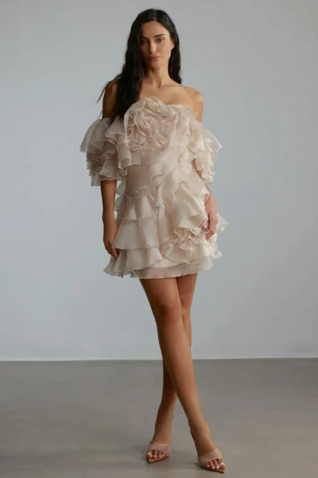 Full-length shot of a model in a light pink, ruffled, off-the-shoulder mini dress. Secondary image