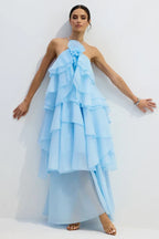 Woman in a light blue tiered ruffle halter gown with arms outstretched.