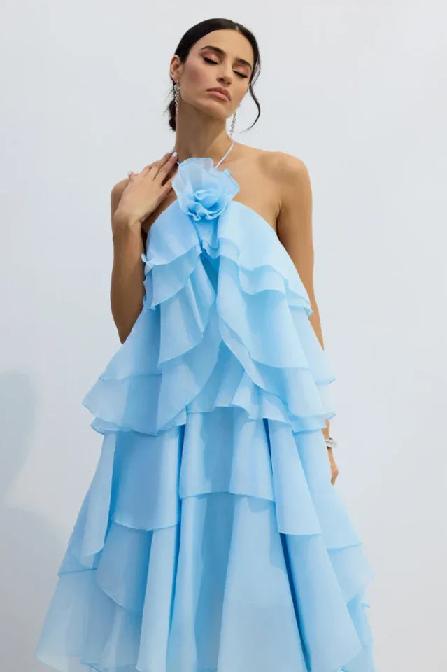 Close-up of a woman wearing a light blue tiered ruffle halter gown with a floral applique.