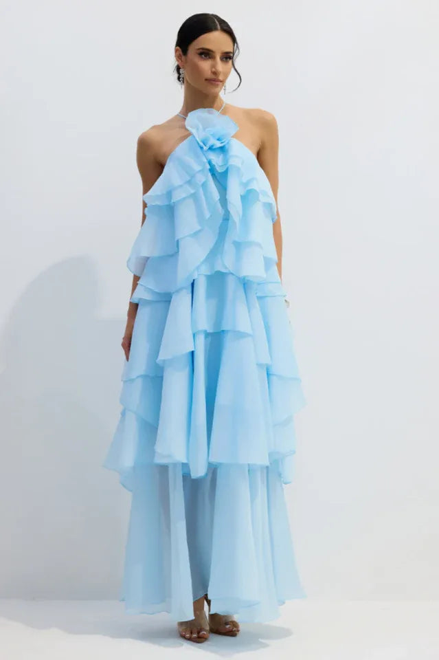 Woman wearing a light blue tiered ruffle halter gown with a floral applique at the neckline.