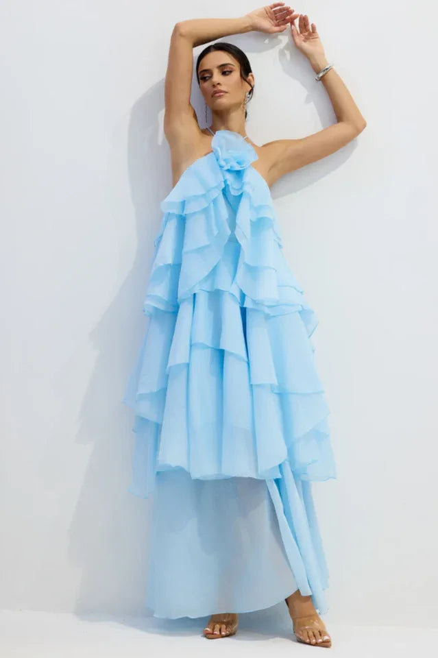 Woman in a light blue tiered ruffle halter gown posing with arms raised.