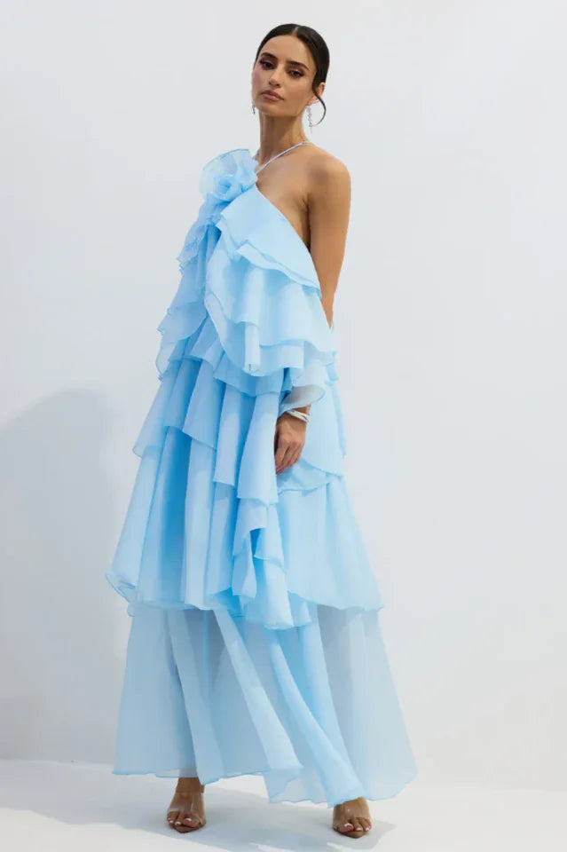 Woman wearing a light blue tiered ruffle gown with one shoulder exposed.