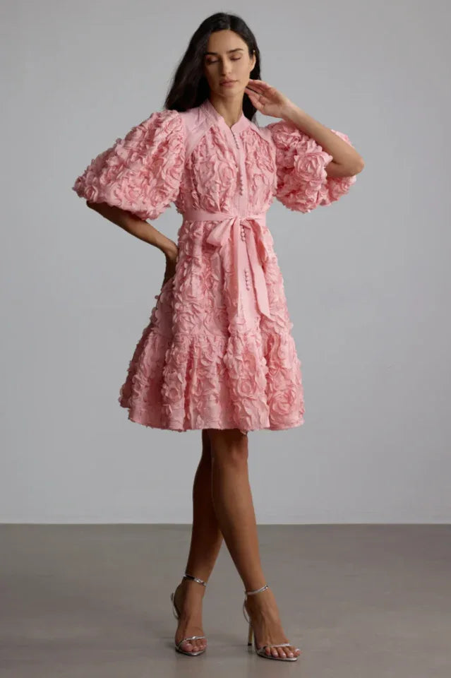 Side view of a woman modeling a pink puff sleeve dress with a self-tie belt