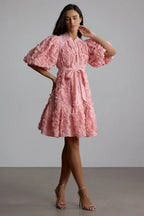 Side view of a woman modeling a pink puff sleeve dress with a self-tie belt