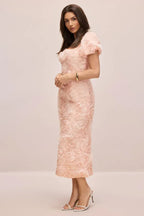 Side view of a woman in a pink floral appliqué dress