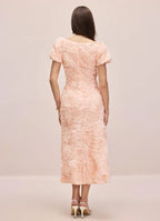 Back view of a woman wearing a pink midi dress with puff sleeves and floral details
