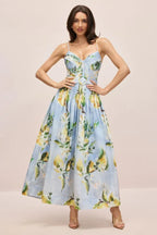 Woman wearing a light blue midi dress with a lemon print, spaghetti straps, a sweetheart neckline, and a full skirt.