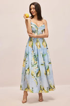 Woman in a light blue midi dress with a lemon print, holding a lemon.