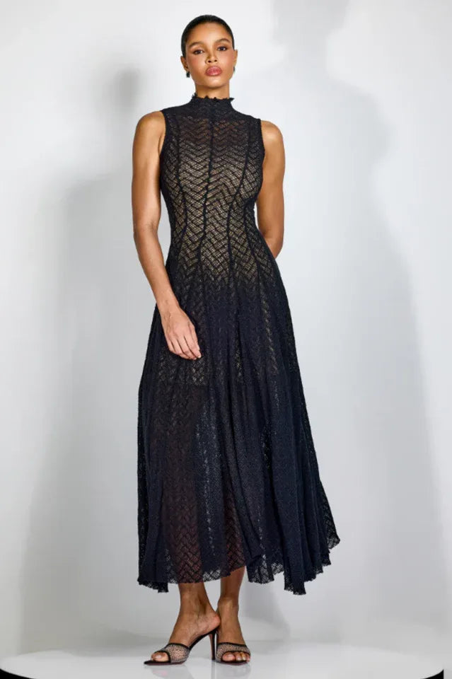 Woman wearing a black sleeveless mock neck midi dress with a chevron knit pattern