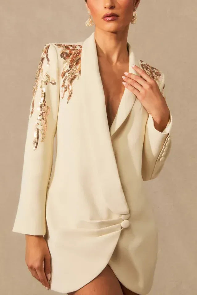 Close-up of the embellished shoulder and neckline of a cream tuxedo dress.