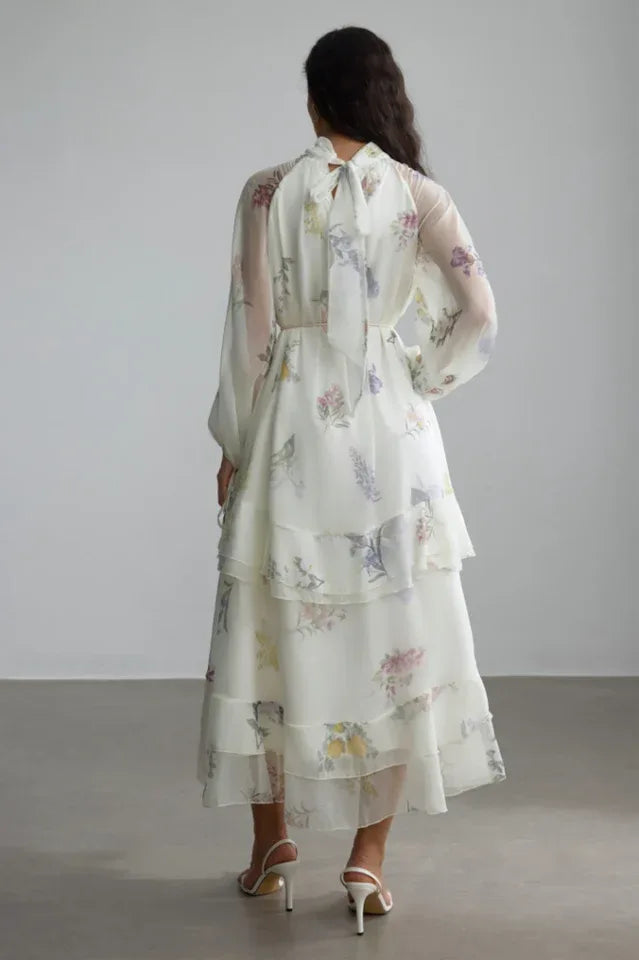 Back view of the white floral print chiffon tiered midi dress with a bow at the neckline.