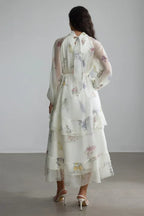 Back view of the white floral print chiffon tiered midi dress with a bow at the neckline.