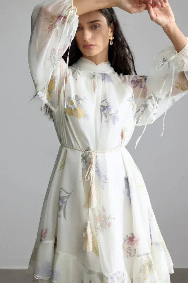 Woman posing with her hands raised, showcasing the details of the floral print chiffon dress.